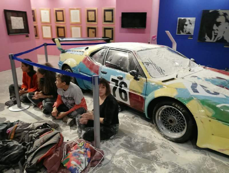 Ultima Generazione protesters sitting in front of the floured Andy Warhol car.