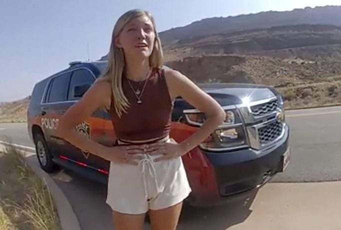Gabby Petito stands in front of a vehicle.