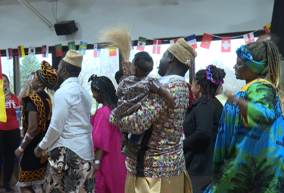 Festival goers wearing traditional clothing from their countries of origin dance.