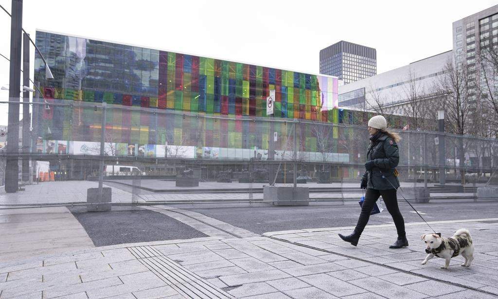 A woman walks her dog outside the fenced-off perimeter of the Montreal Convention Centre ahead of the COP15 UN conference on biodiversity on Dec. 1, 2022.