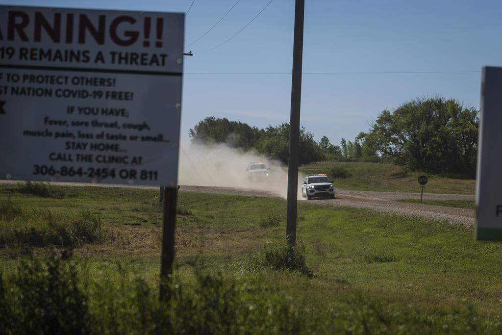 Canadian law enforcement personnel rush to surround a home on the James Smith Cree First Nation reservation in Saskatchewan on Sept. 6, 2022.