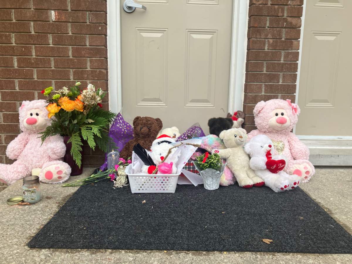 A memorial of flowers, candles, children's drawings and stuffed teddy bears can be seen on the front steps of 416 Boulee Street as London, Ont., police investigate after two bodies were found in a townhouse complex on Saturday, Dec. 10, 2022.