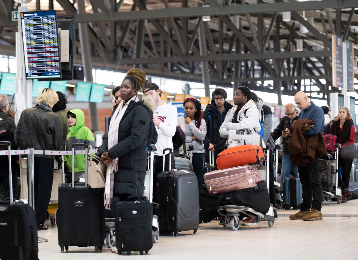 Travellers line up at the Ottawa International Airport, as airlines cancel or delay flights during a major storm in Ottawa, on Friday, Dec. 23, 2022.