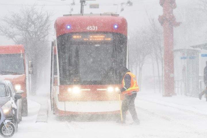 A streetcar driver works to clear ice from a track switch during a snowstorm in Toronto on Friday, December 23, 2022. A winter storm warning is in place for most of southern Ontario.