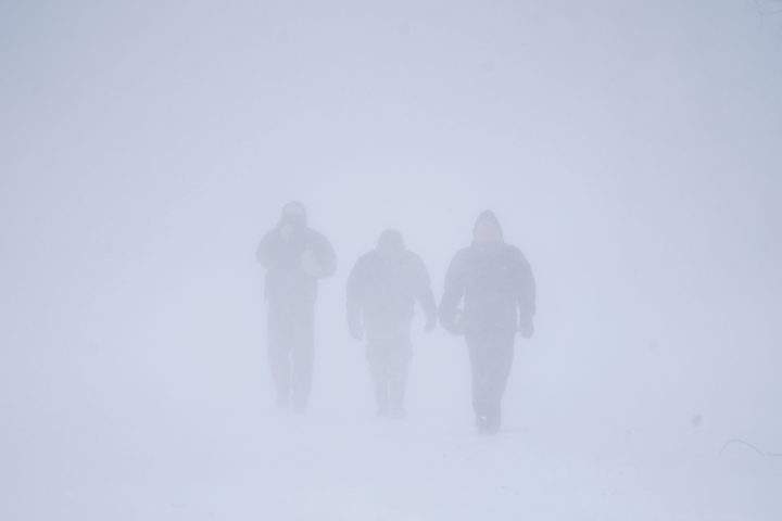 Three men walk down Richmond Avenue in whiteout conditions during a sustained blizzard in Buffalo, N.Y. on Saturday, Dec. 24, 2022.