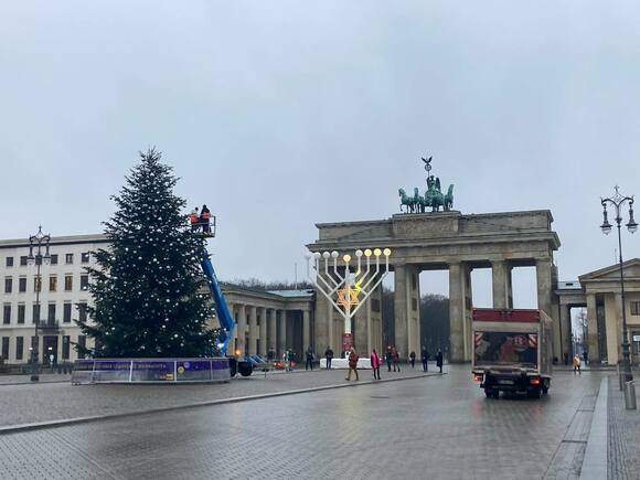 The Christmas tree and hydraulic lifted platform in front of the Brandenburg Gate. A large menorah is seen in the background.