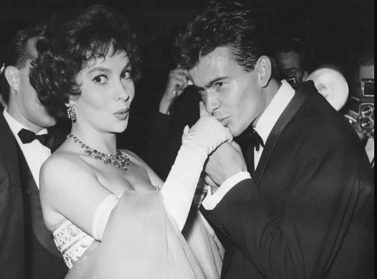 A black and white photo. Horst Buchholz kisses the hand of Gina Lollobrigida.