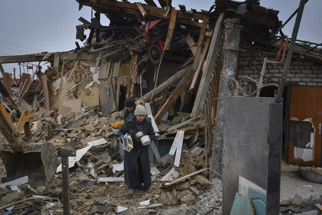 Local residents carry their belongings as they leave their home ruined in the Saturday Russian rocket attack in Zaporizhzhya, Ukraine, Sunday, Jan. 1, 2023.