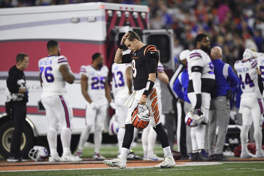 Cincinnati Bengals quarterback Joe Burrow (9) pauses as Buffalo Bills’ Damar Hamlin is examined by medical staff during the first half of an NFL football game on Jan. 2 in Cincinnati.