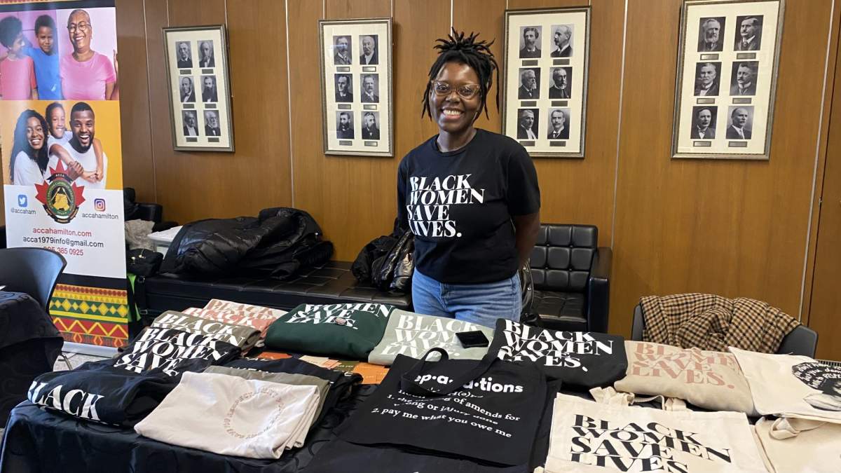 Rose Senat poses with t-shirts and tote bags from her business 'Take Up Space' during the kick-off for Black History Month at Hamilton city hall.