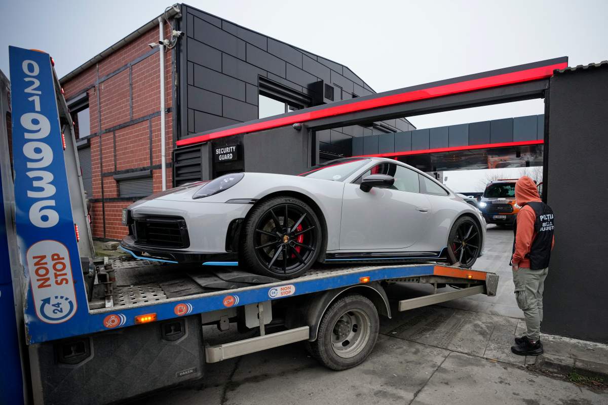 A police officer looks on as a luxury vehicle which was seized in a case against media influencer Andrew Tate, is towed away, on the outskirts of Bucharest, Romania, Saturday, Jan. 14 2023. Prosecutors seized several luxury vehicles after Tate lost a second appeal this week at a Bucharest court, where he challenged the seizure of assets in the late December raids, including properties, land, and a fleet of luxury cars. More than 10 properties and land owned by companies registered to the Tate brothers have also been seized so far.