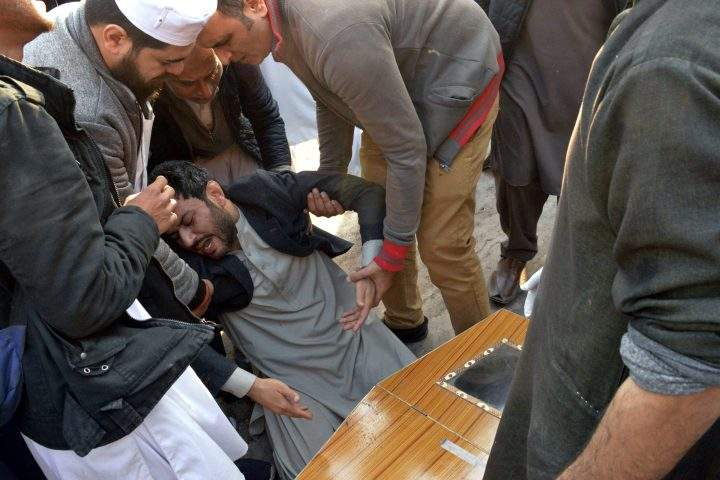 People comfort a man mourning next to the coffin of his family member, who was killed in a suicide bombing inside a mosque in Peshawar, Pakistan, Monday, Jan. 30, 2023.