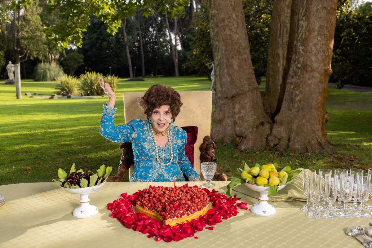 Gina Lollobrigida sitting at a table covered in rose petals.