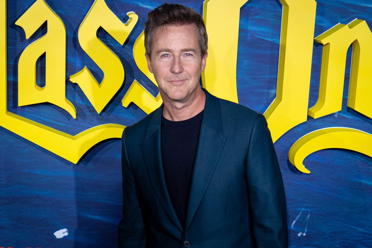 Edward Norton on a red carpet. He is wearing a blue suit jacket.