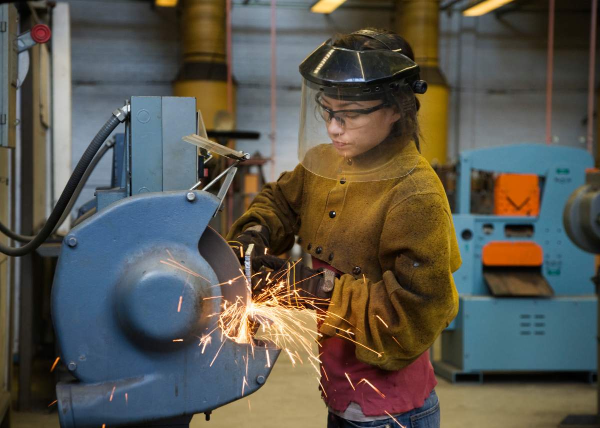 Mixed race female welder using machinery