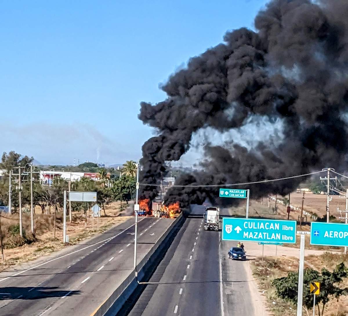 Vehicles on fire block a highway in Mazatlan, Mexico on Jan. 5, 2023, with smoke rising from the wreckage.