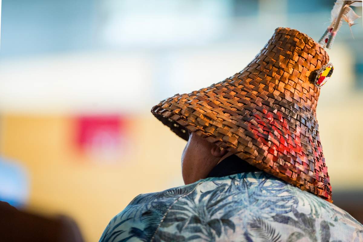 A woman is pictured from behind, she's wearing a cedar hat the the background is blurred.
