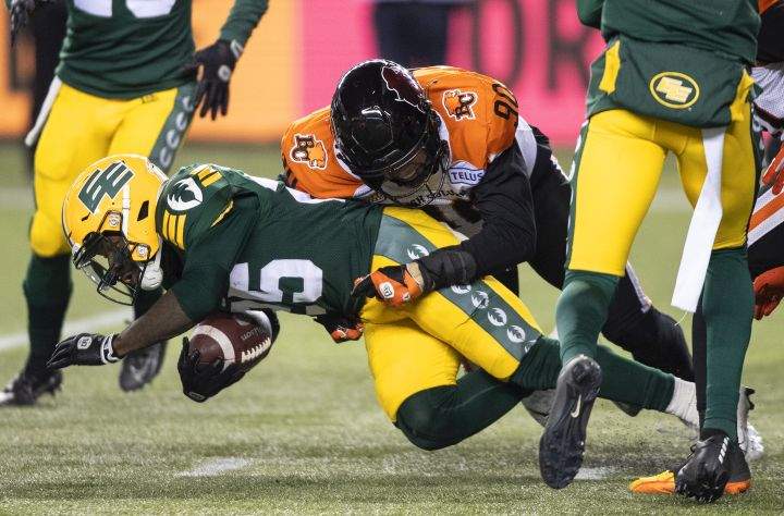 B.C. Lions' Mathieu Betts (90) tackles Edmonton Elks' Christian Saulsberry (25) during second half CFL action in Edmonton, Alta., on Friday October 21, 2022. 