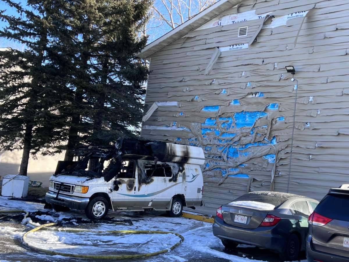 Remnants of a van following a fire on Jan. 22, 2023, can be seen, along with damage to siding on a nearby condo.