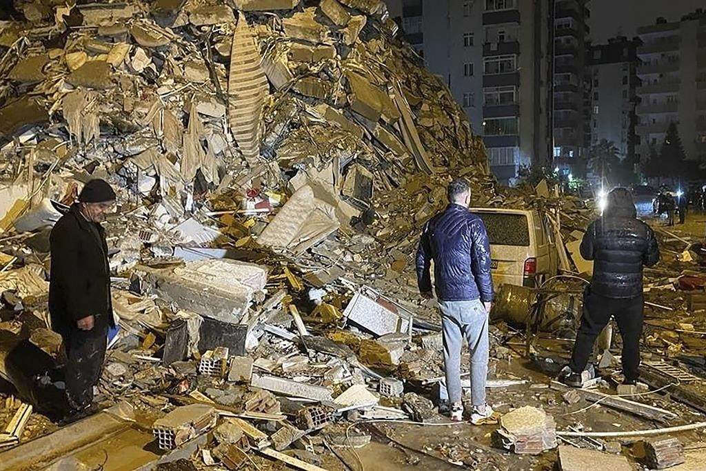 People try to reach trapped residents inside collapsed buildings in Diyarbakir, southern Turkey, early Monday, Feb. 6, 2023.