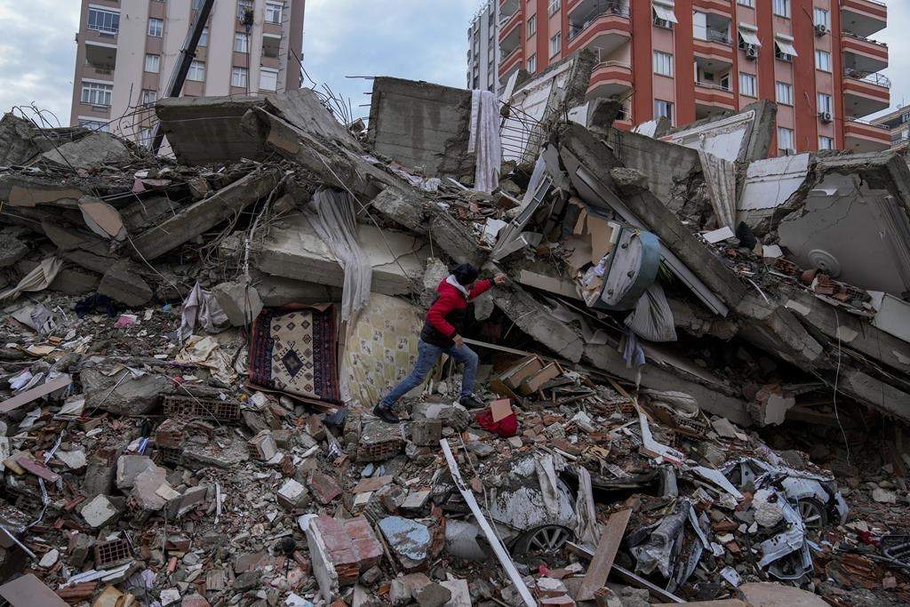 A man walks among rubble as he searches for people in a destroyed building in Adana, Turkey, Monday, Feb. 6, 2023. (AP Photo/Khalil Hamra)