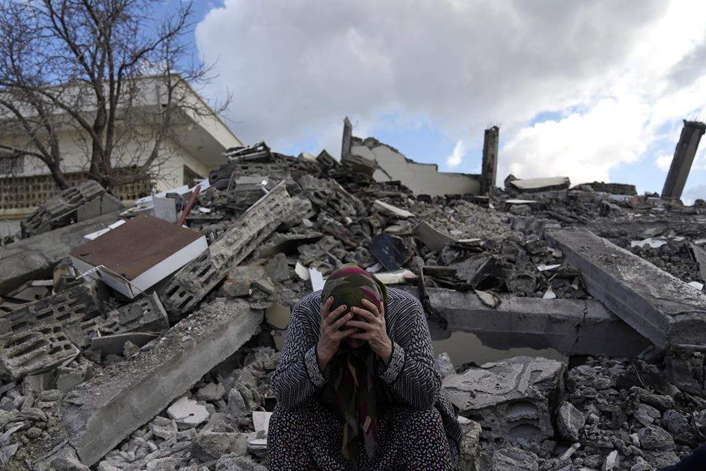 A woman sits on the rubble as emergency rescue teams search for people under the remains of destroyed buildings in Nurdagi town on the outskirts of Osmaniye city southern Turkey, Tuesday, Feb. 7, 2023.