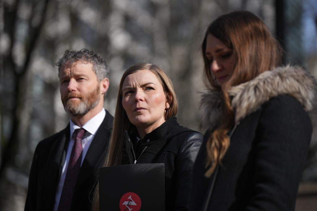 Photojournalist Amber Bracken, centre, lawyer Sean Hern, back left, and Emma Gilchrist, editor-in-chief and executive director of The Narwhal, listen during a news conference after filing a lawsuit at B.C.