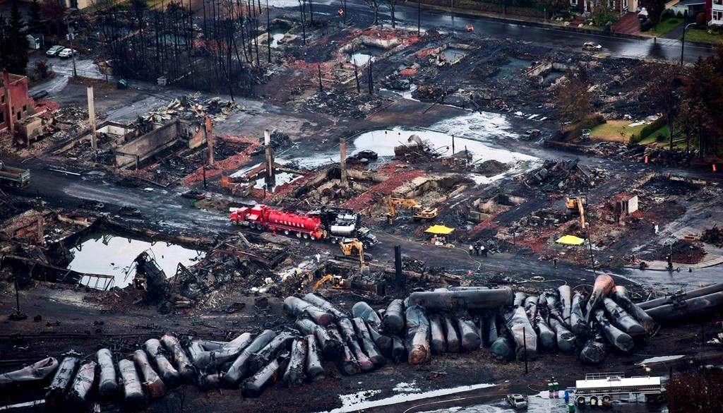 Workers comb through debris after a train derailed Saturday, July 9, 2013 causing explosions of railway cars carrying crude oil in Lac-Mégantic, Quebec. The federal government is moving to acquire land so that it can build a rail bypass in Lac-Mégantic, Que., nearly 10 years after a downtown freight train derailment killed 47 people. THE CANADIAN PRESS/Paul Chiasson.