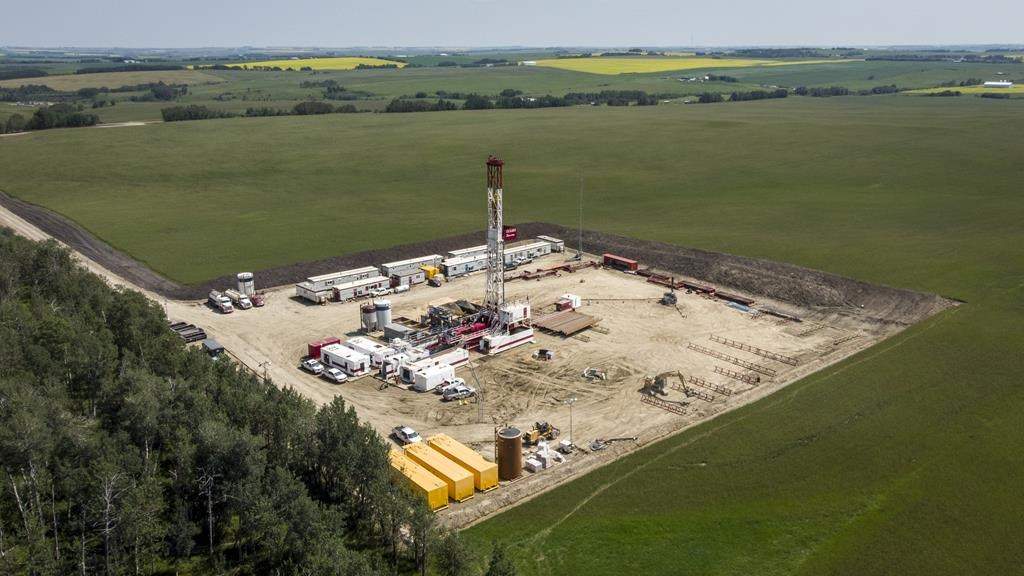 An oil drilling rig operates surrounded by canola and hay fields near Cremona, Alta., Monday, July 12, 2021.