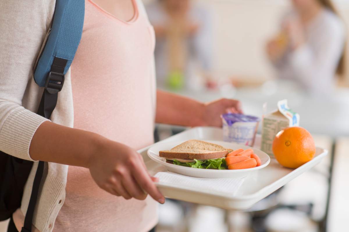 A girl holding a school lunch tray.