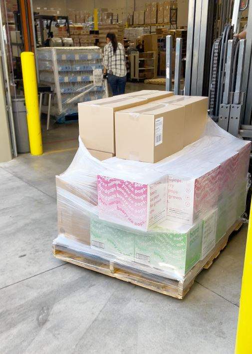 Cases of Hardpops being moved by a forklift.