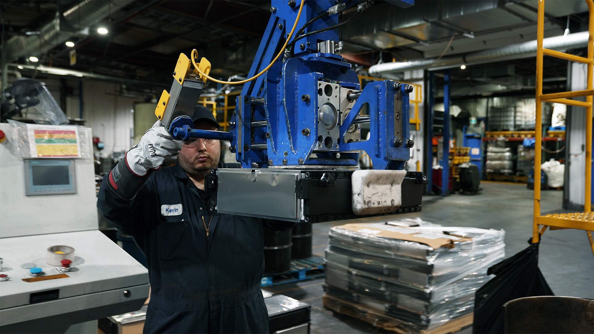 A worker at Li-Cycle's Kingston facility uses a lift assist to move EV battery modules from a skid to the conveyor.