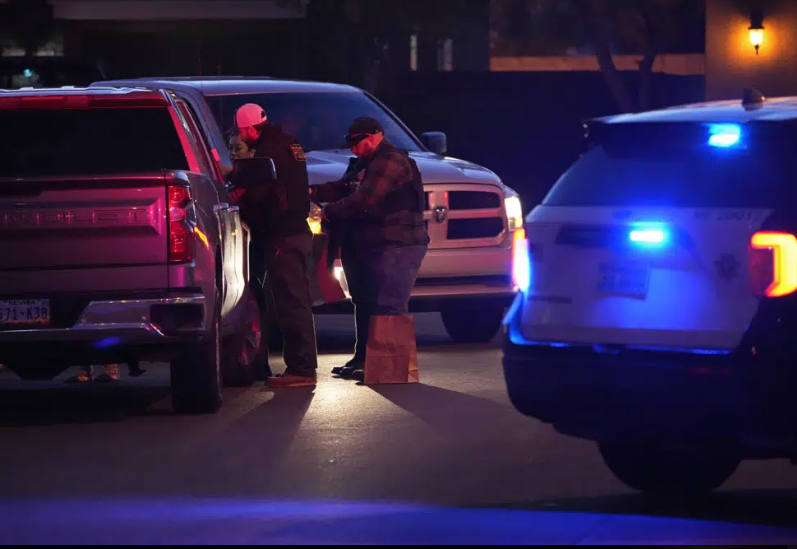 Two people stand beside a truck. There is a police vehicle in the frame.