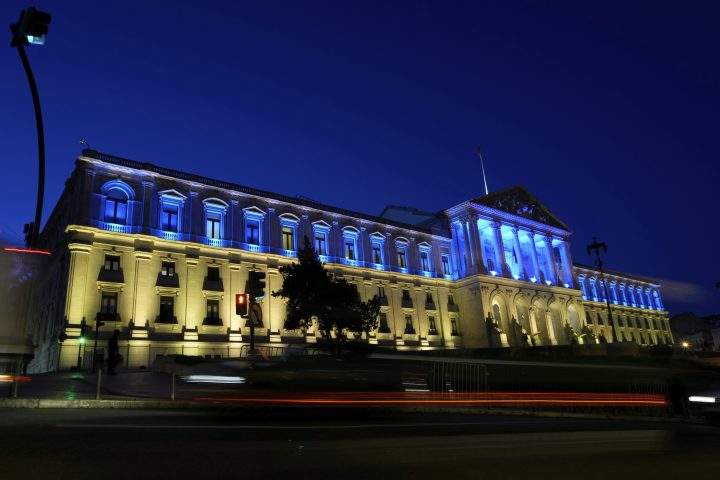 Vehicles drive past the Portuguese Parliament lit with the Ukrainian flag colours to mark the one-year anniversary of the invasion of Ukraine, in Lisbon, as night falls Thursday, Feb. 23, 2023.
