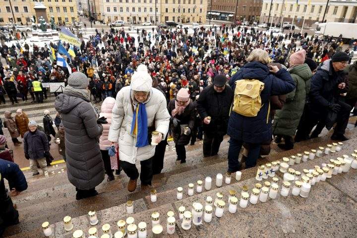 People placing candles on the steps of the Helsinki Cathedral at the Light for Ukraine candlelight memorial event for Ukraine war victims at the Senate Square in Helsinki, Finland on Feb. 24, 2023.