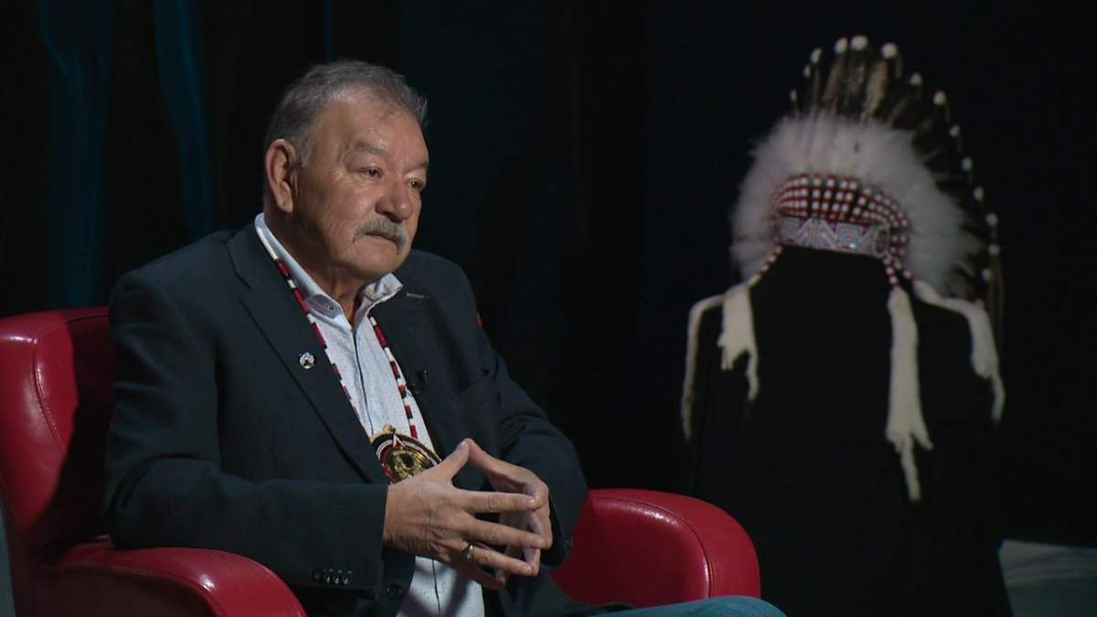 Former Confederacy Chief George Arcand Jr. sits in front of headdress.