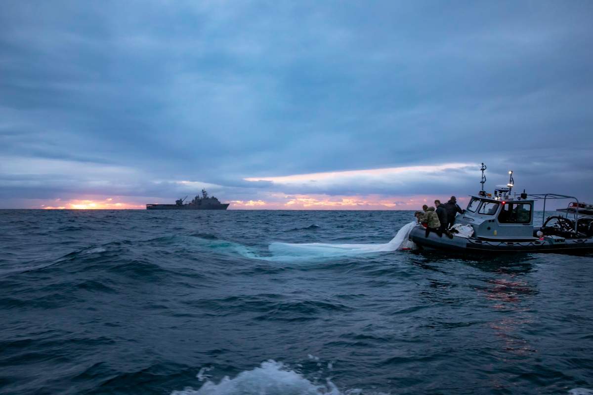 A Navy boat at sea. The sun is setting.