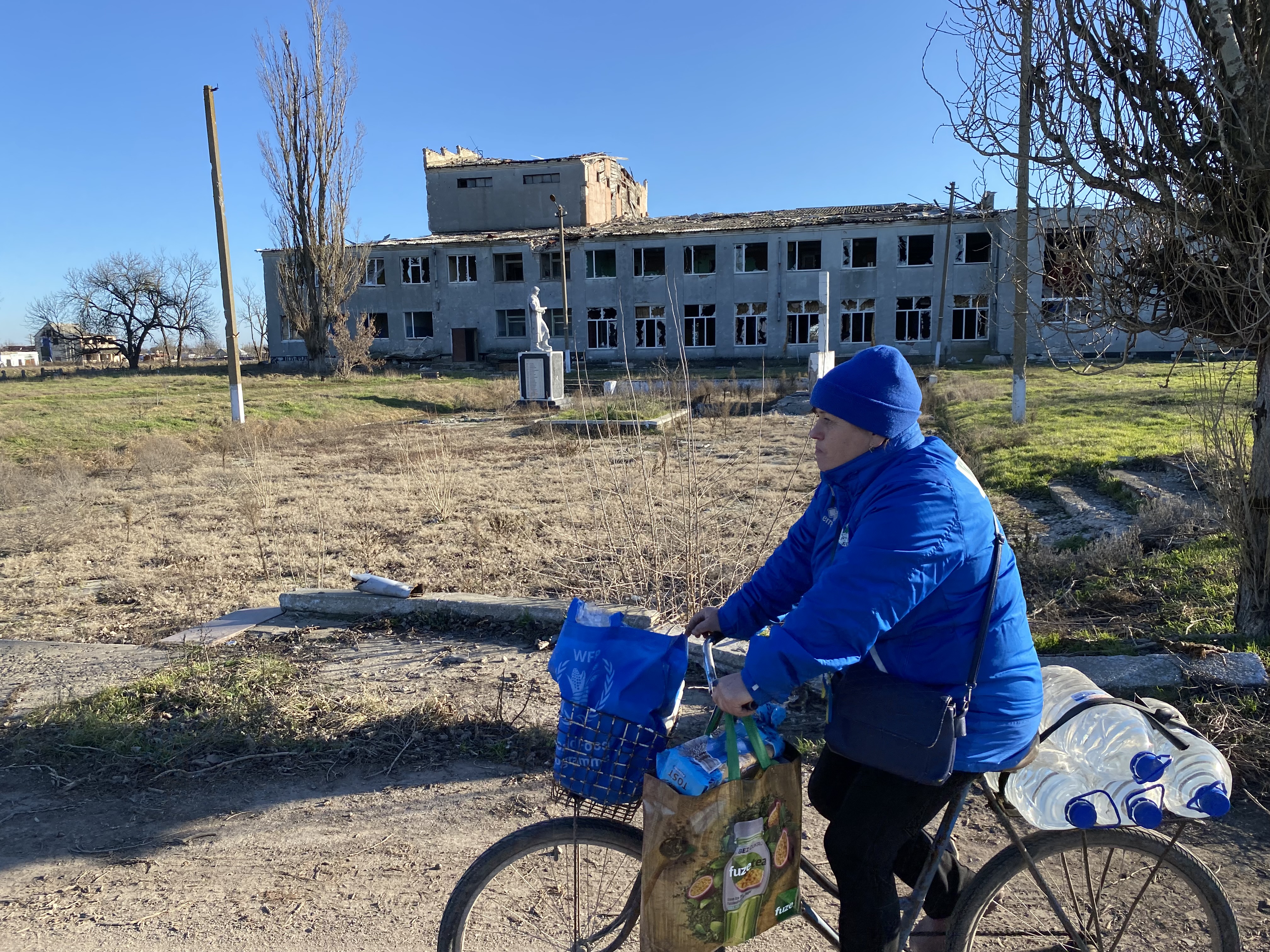 A woman cycles past a war-damaged building in Posad-Pokrovske, Ukraine, Jan. 21, 2023.