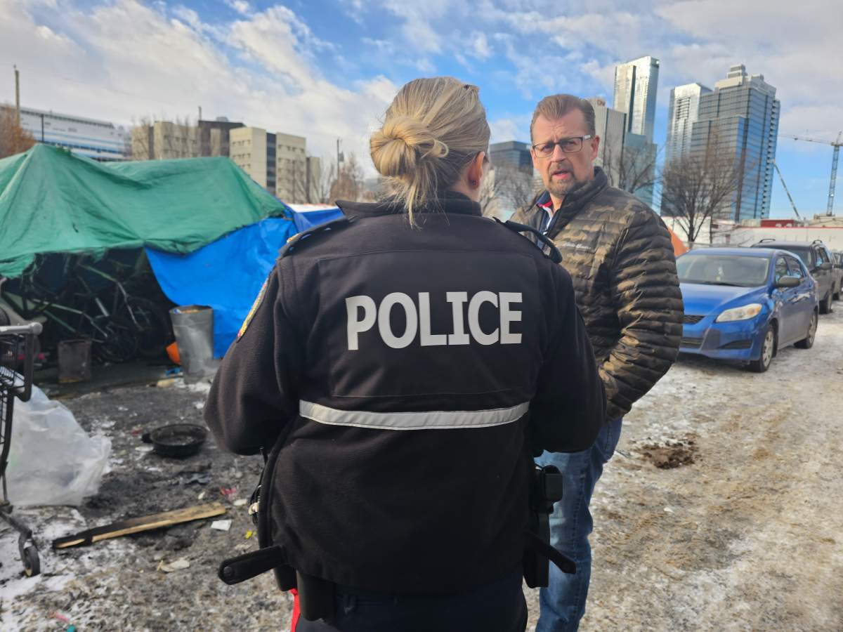 Alberta Minister of Public Safety and Emergency Services Mike Ellis speaking with an Edmonton Police Service officer near a homeless encampment north of downtown Edmonton, Alta. on Thursday, March 2, 2023.