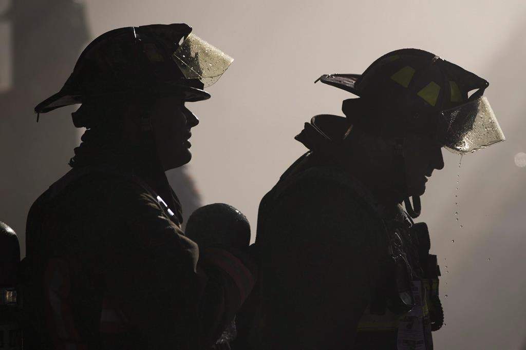 Firefighters take a break from working on a house fire on Argyle street in Toronto, Wednesday July 5, 2017. Ontario is expanding workplace coverage of cancers for firefighters. THE CANADIAN PRESS/Mark Blinch.