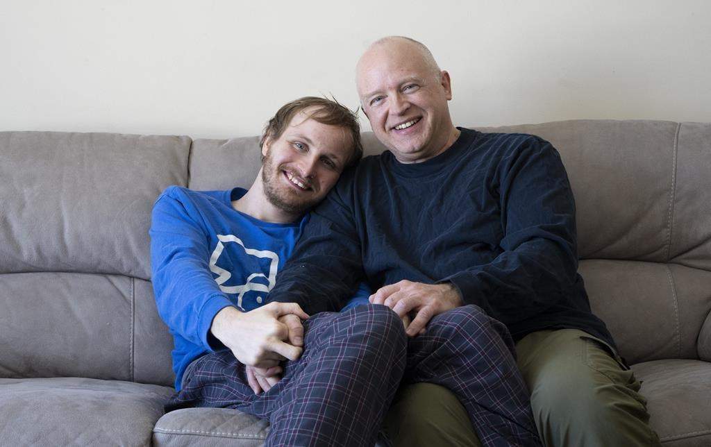 Andrew Kavchak and his son Steven pose for a photo on the sofa in their home in Ottawa, Friday, March 3, 2023. Kavchak, 60, a former federal public servant, retired to provide care for his son Steven, 22, who lives with autism spectrum disorder. Kavchak was told the wait-list for his son Steven to enter a group home would be 10 years long.