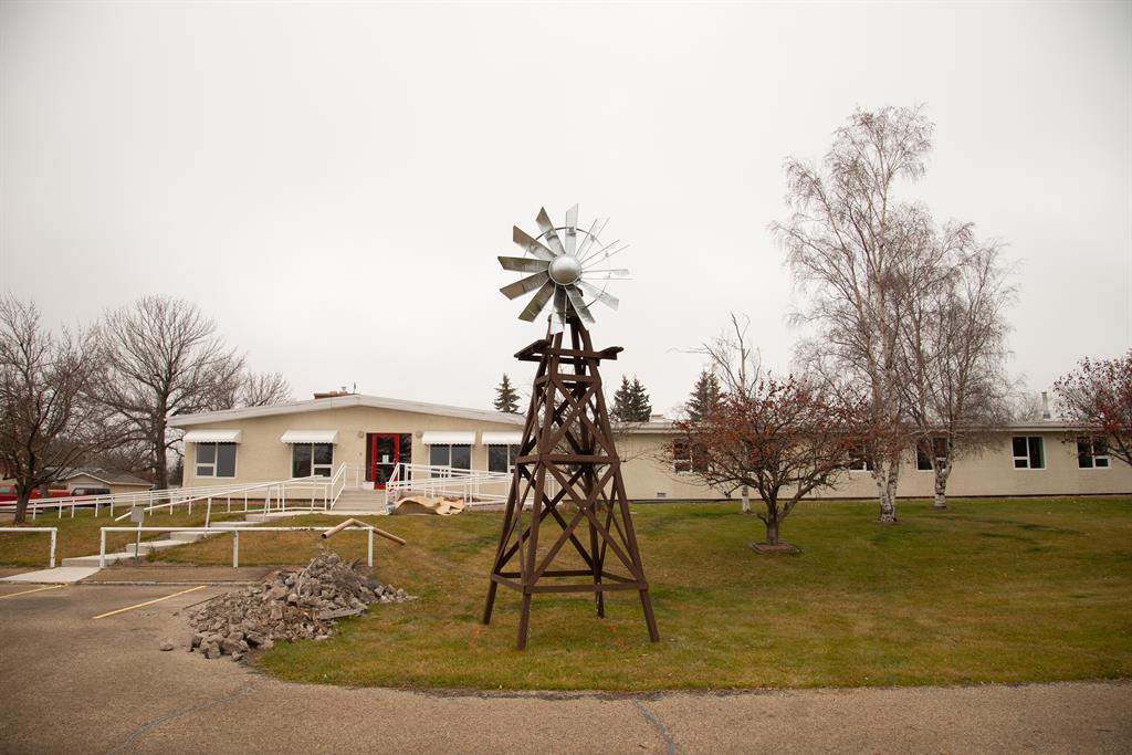 A large facility with beige siding and a ramp entrance has a small windmill out front.