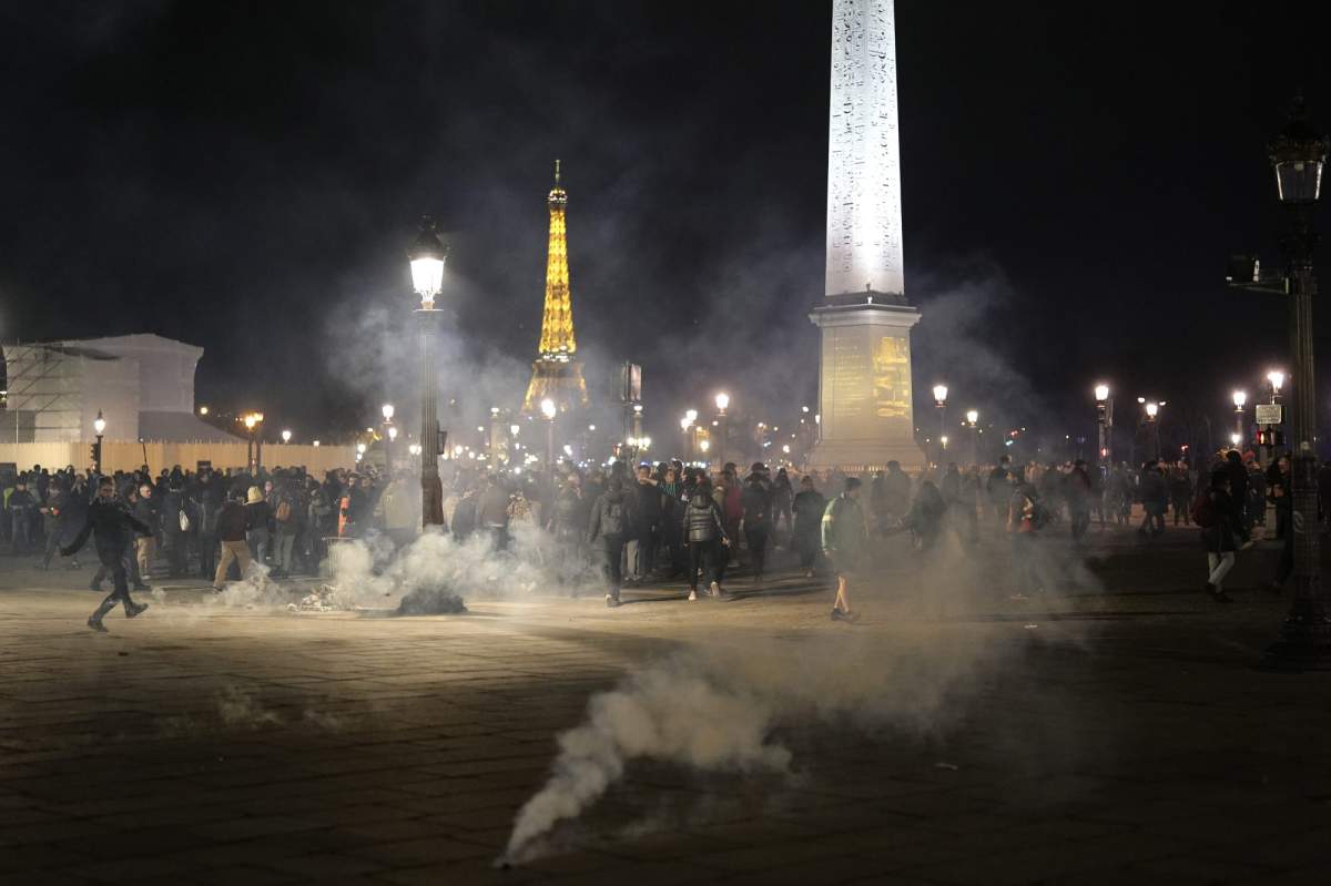 Protesters stand in a cloud of teargas after a demonstration in Paris, Thursday, March 16, 2023.