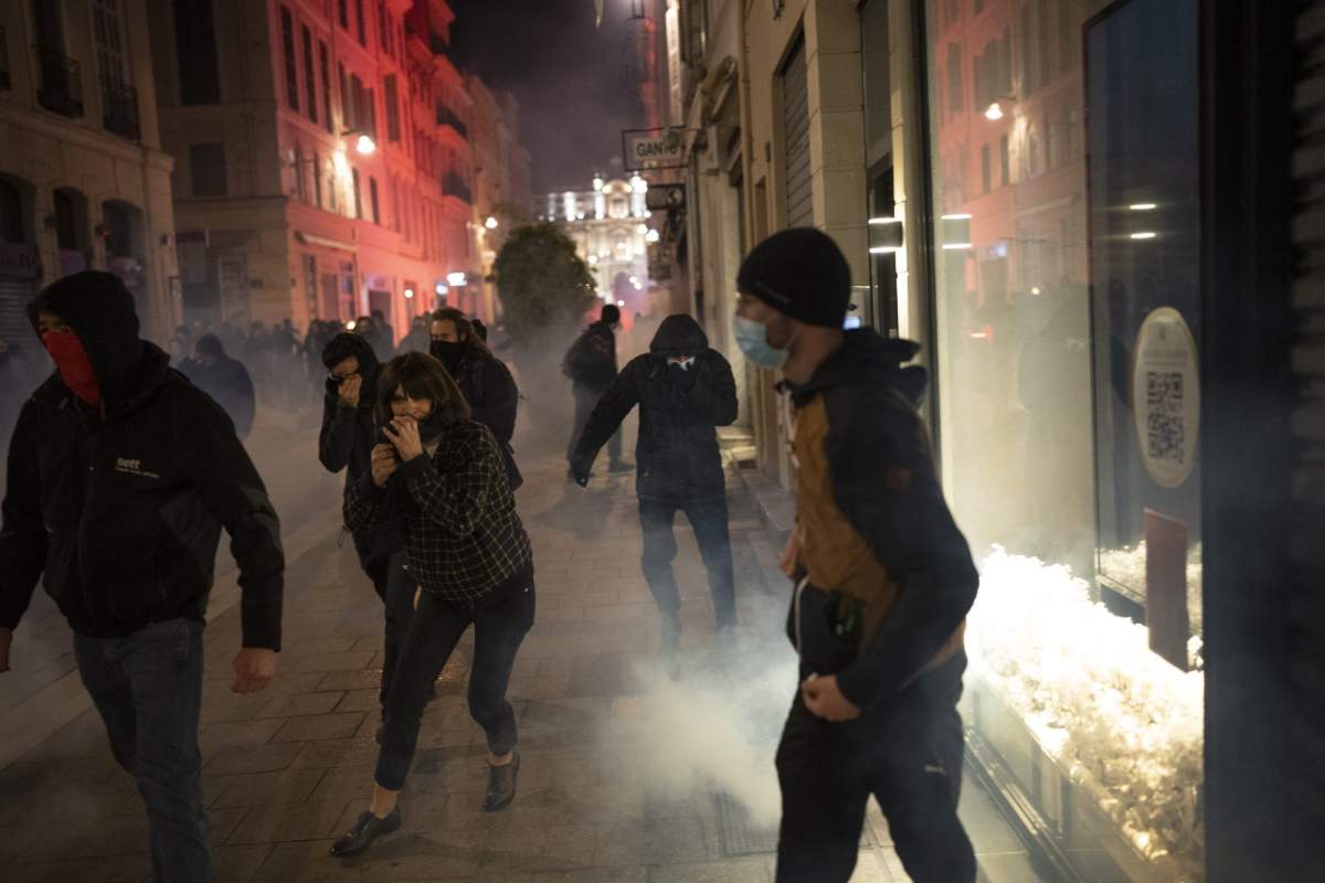 People run from tear gas fired by French riot police during a demonstration in Marseille, southern France, Thursday, March 16, 2023.