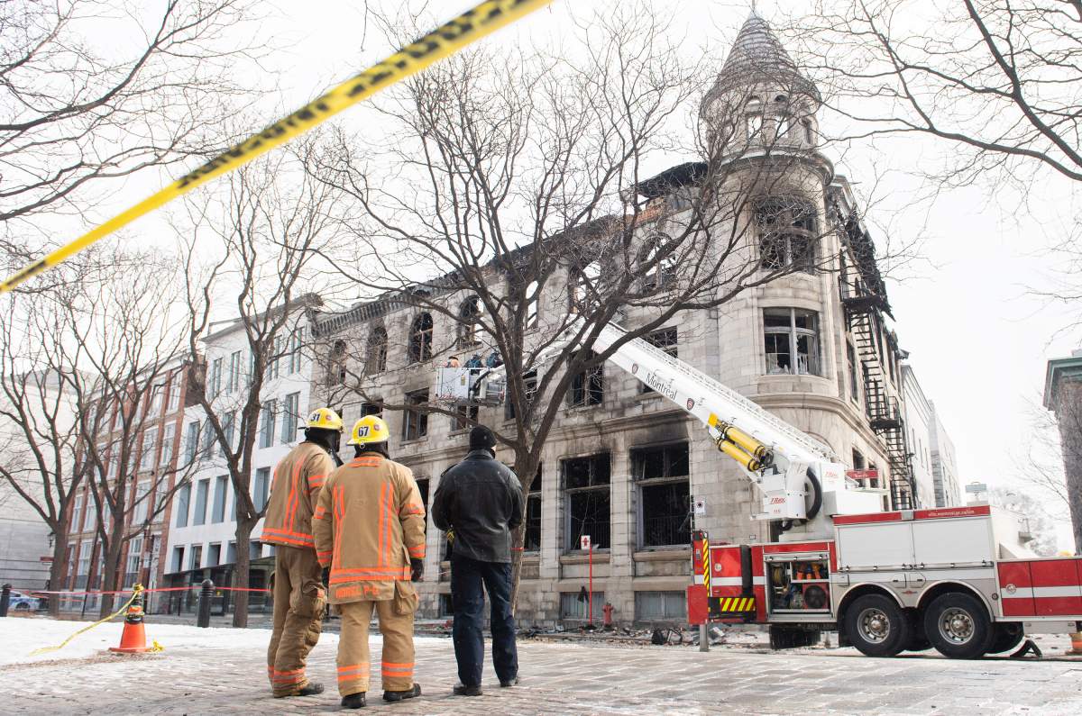 Investigators and firefighters survey the scene following a fire in Old Montreal, Sunday, March 19, 2023, that gutted a heritage building. Several people are still unaccounted for.
