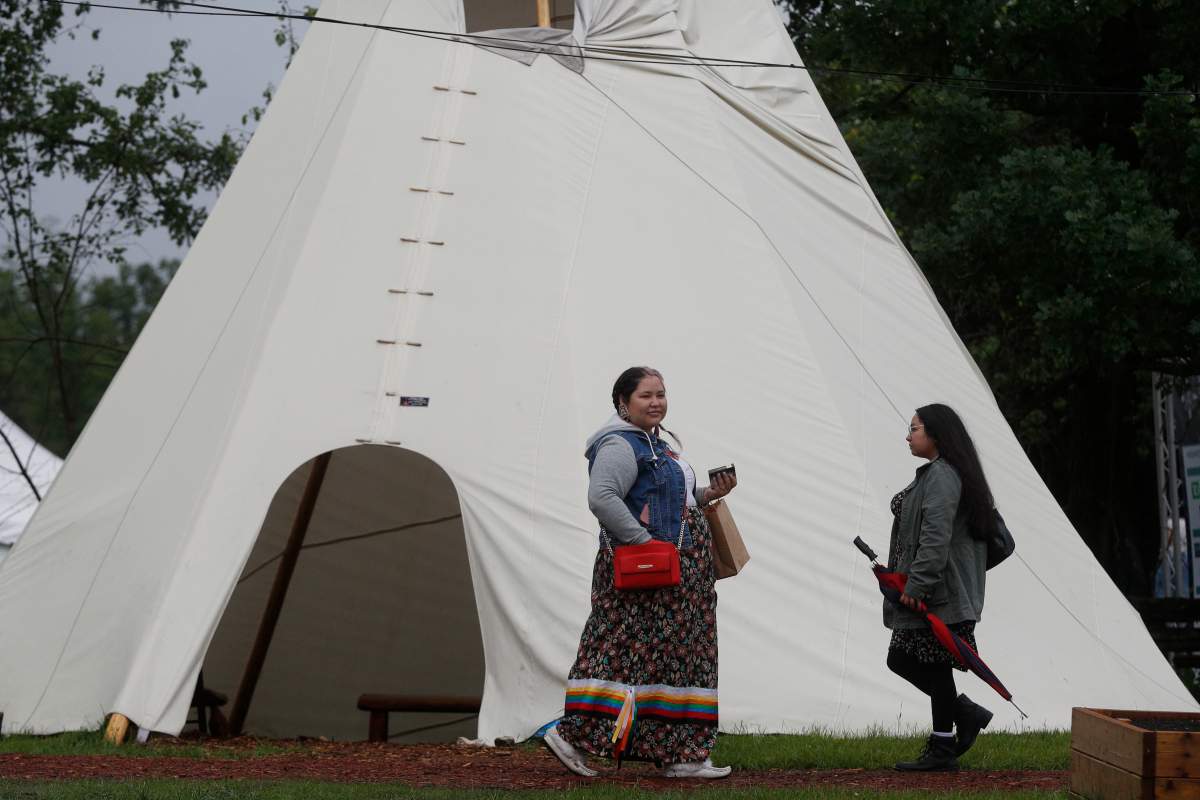 People walk past a tipi during the National Indigenous Peoples Day celebrations at Mādahòkì Farm in Ottawa, Ontario on Tuesday, June 21, 2022. 