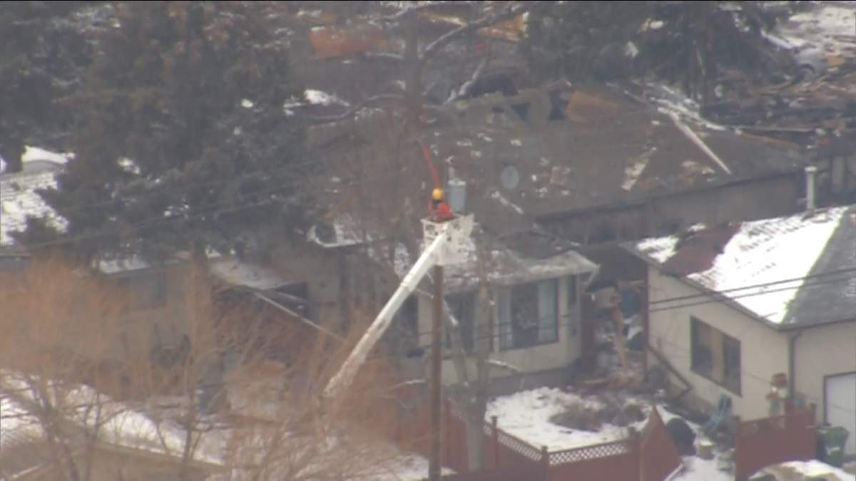 A utilities worker is seen working on power lines following a house explosion in Calgary in March 27, 2023.