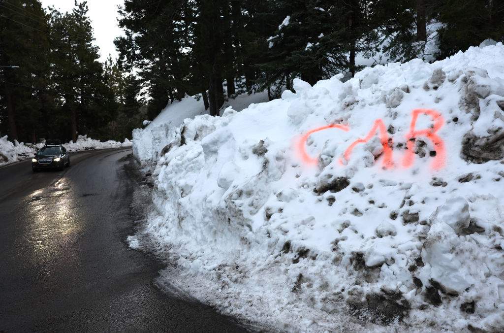Spray paint indicates where a car is buried in a snowbank after a series of winter storms dropped more than 100 inches of snow in the San Bernardino Mountains in Southern California on March 8, 2023 in Crestline, Calif.