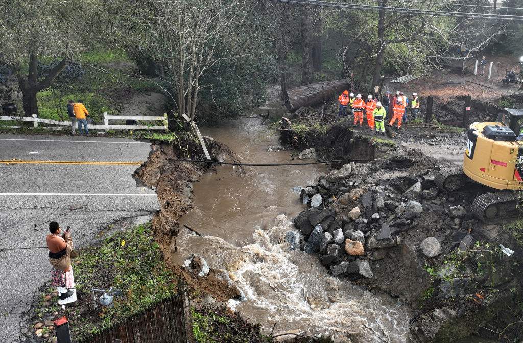 In an aerial view, workers make emergency repairs to a road that was washed out heavy rains on March 10, 2023 in Soquel, Calif.