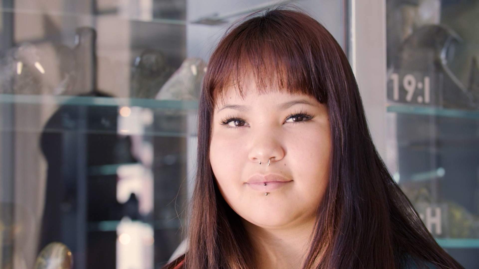 Marisa is a young woman with long, dark auburn hair and face framing bangs. She's looking into the camera. She had dark brown eyes.
